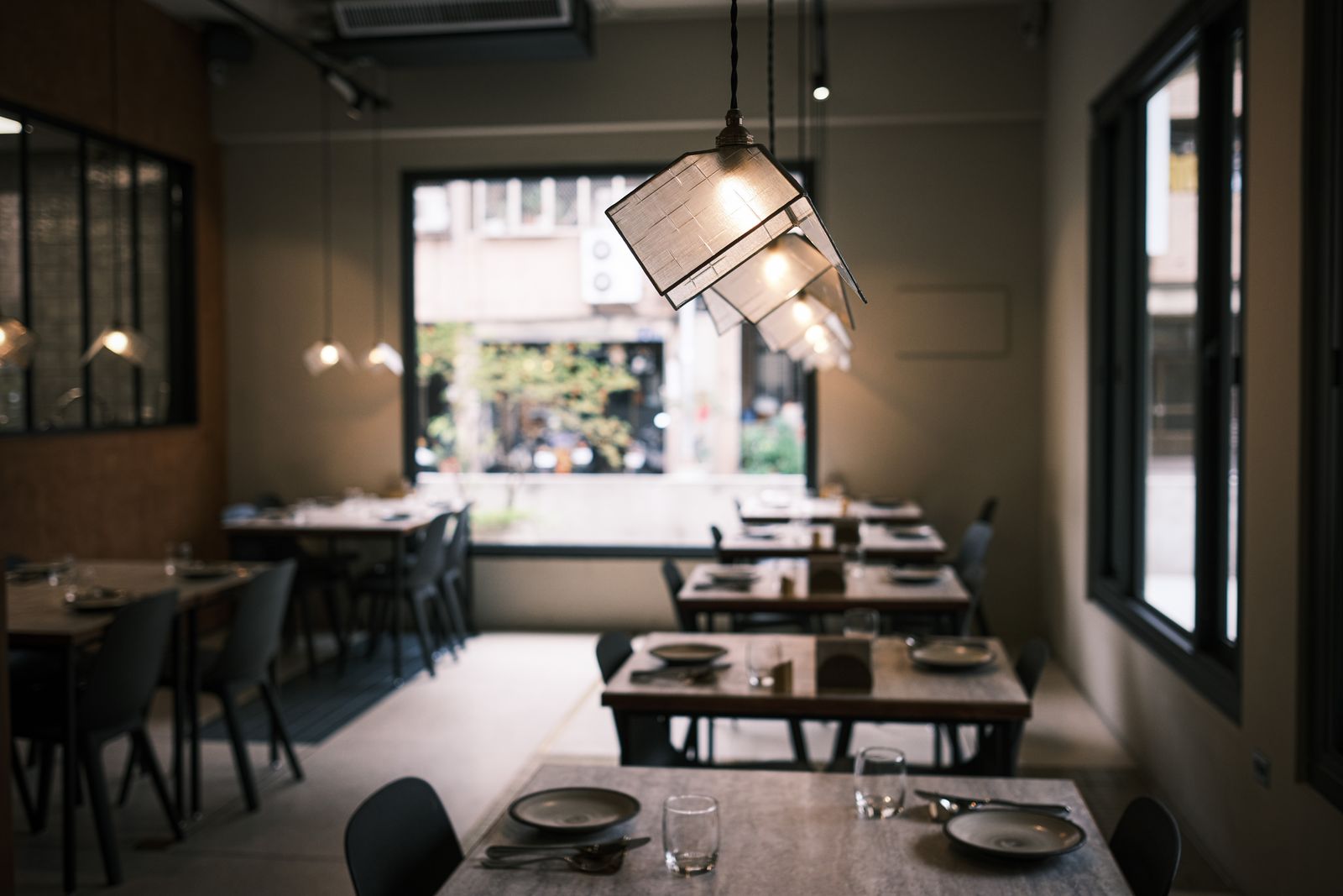 Modern restaurant interior with hanging lights, polished floors, and arranged tables