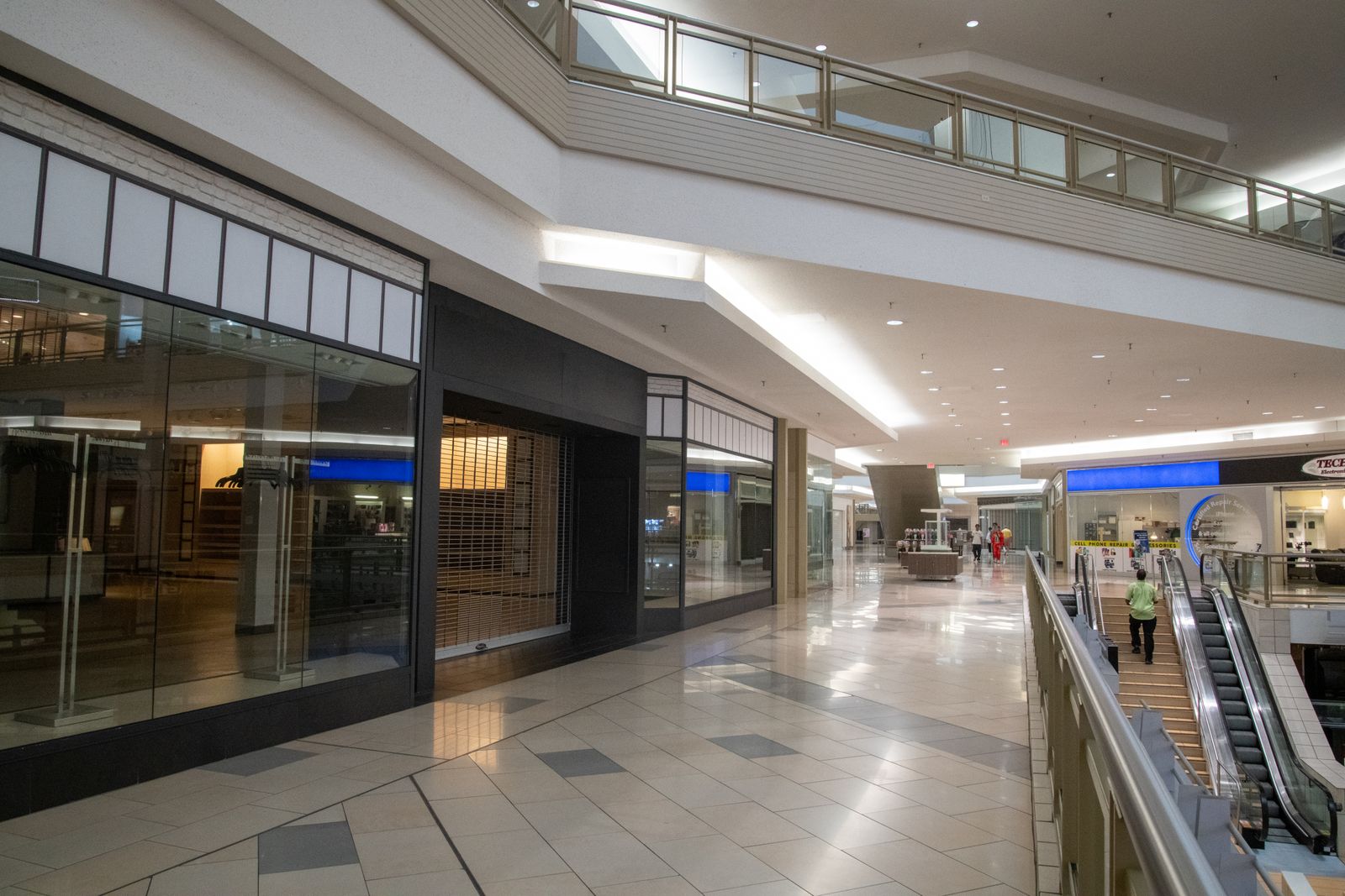 Clean, polished retail concourse with storefronts and escalators