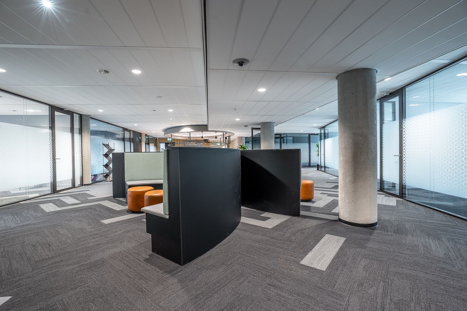 Clean commercial office floor with carpet tile, glass partitions and meeting pods